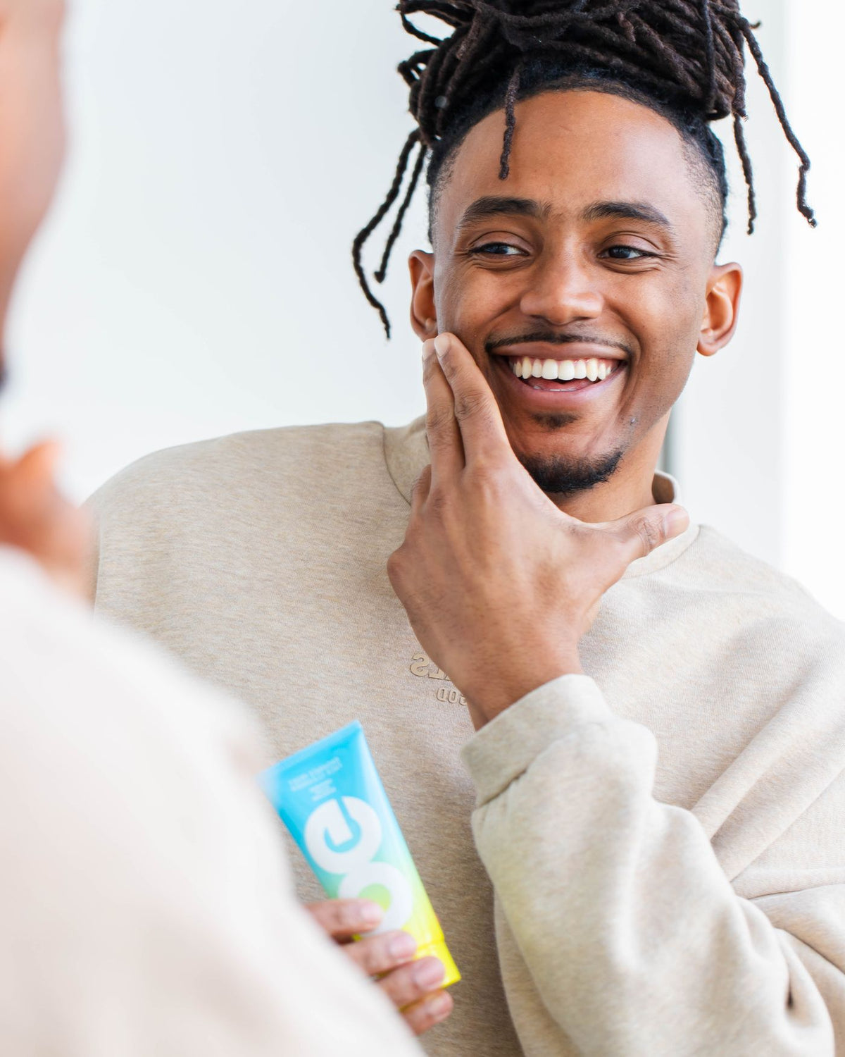 Man at the mirror holding Reset Face Cleanser